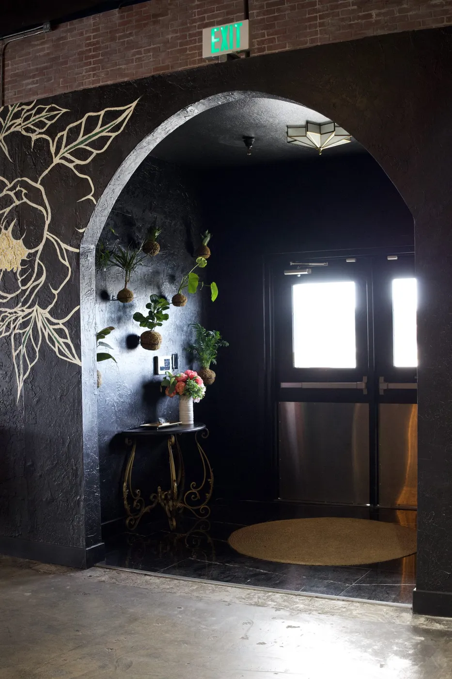 Hand-painted floral accent wall against exposed brick in event venue remodel